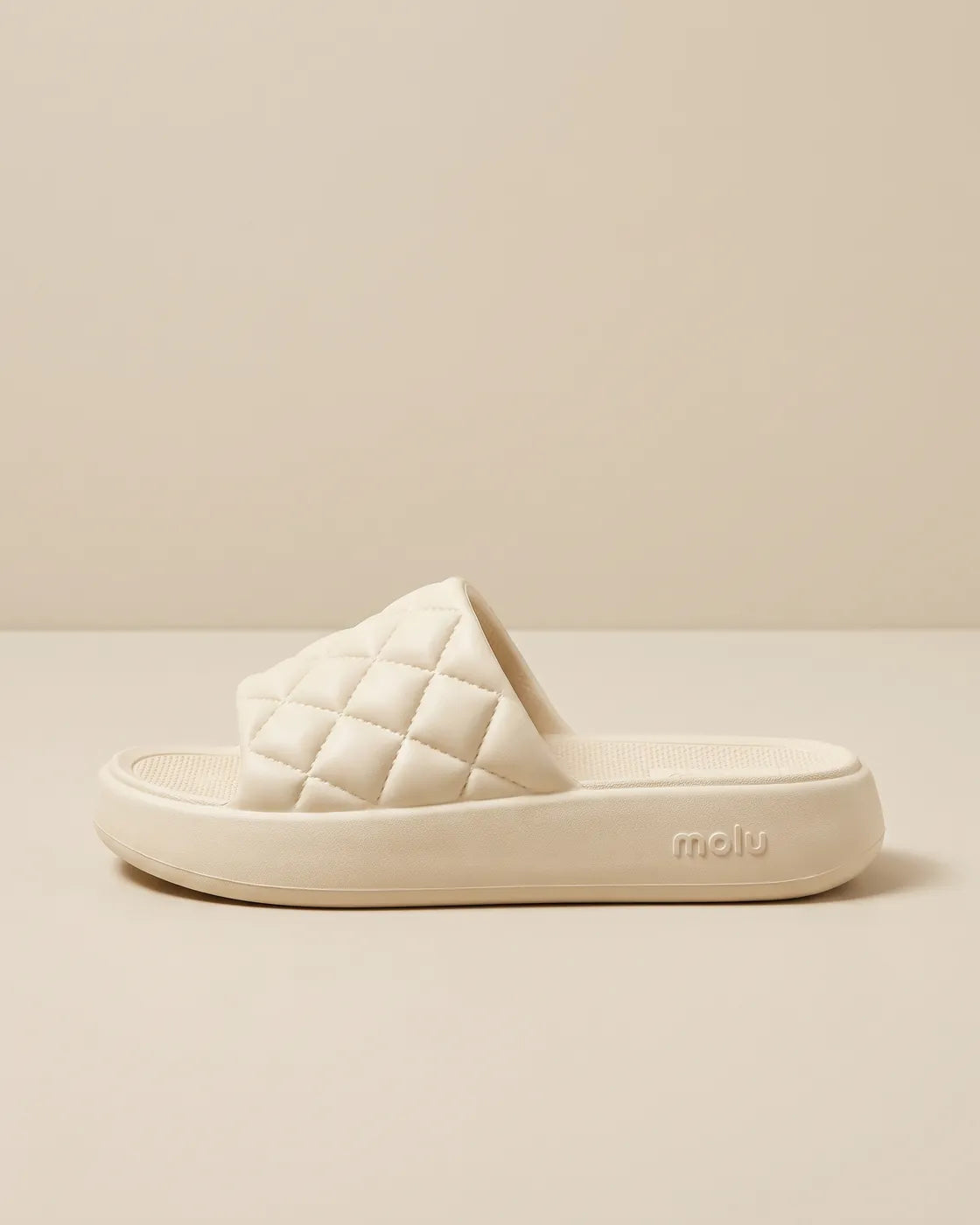 Chinelo molu Luxo bege, de lado, com a tira matelassê e o nome molu gravado no solado